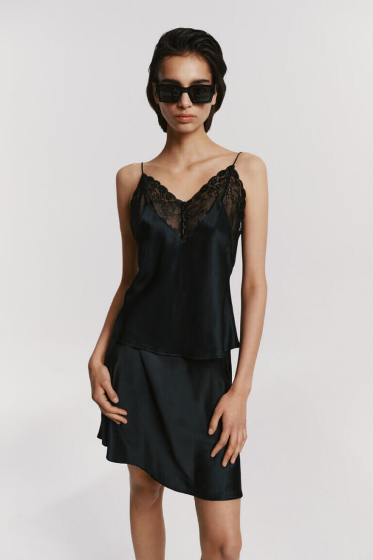 Mannequin portant le top en soie noire à dentelle d'atthrea et la mini-jupe en soie assortie.