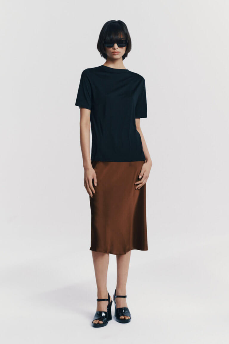 Model showcasing Atthrea's black silk T-shirt paired with a silk skirt