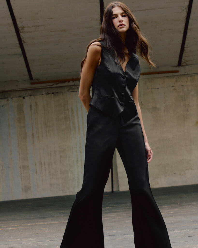Modella mostra ispirazione per outfit in seta. Gilet nero in seta abbinato a pantaloni eleganti in seta.