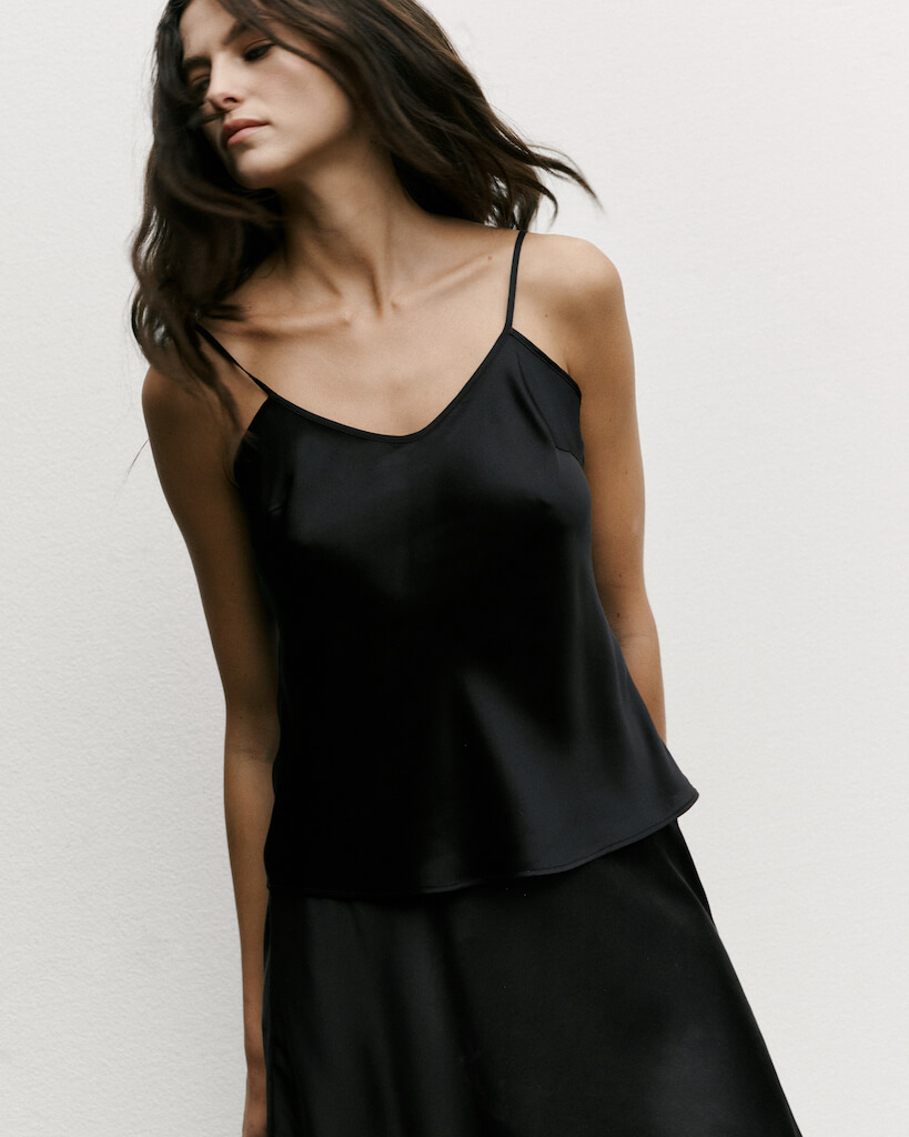 Model wearing classic silk top in black - chic minimalism made from 100% silk satin.