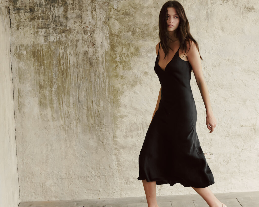 Model showcases a flowing atthrea's silk maxi dress in black.